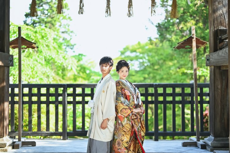 緑をバックに背中合わせの新郎新婦