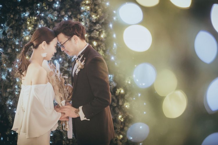キラキラ輝くイルミネーションに囲まれおでこを寄せる新郎新婦