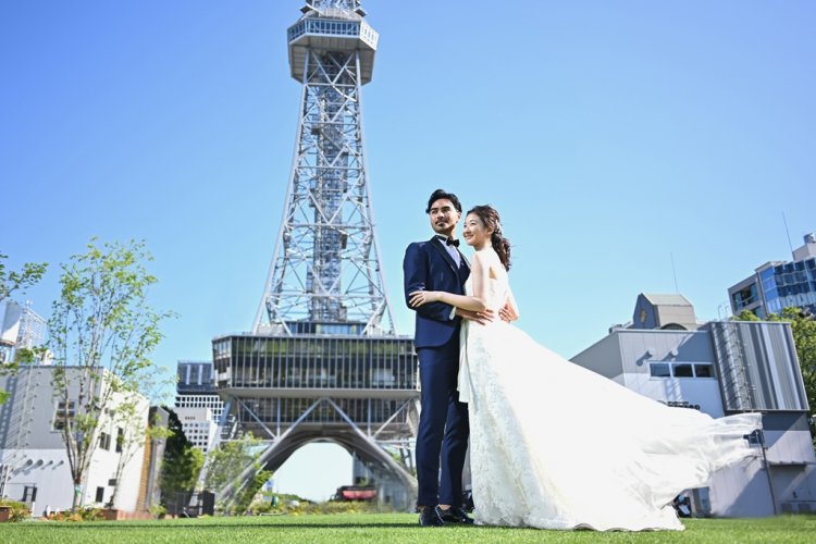 ミライタワー前の芝生で景色を眺める新郎新婦