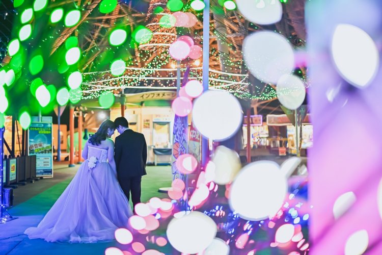 イルミネーションに包まれおでこを合わせる新郎新婦