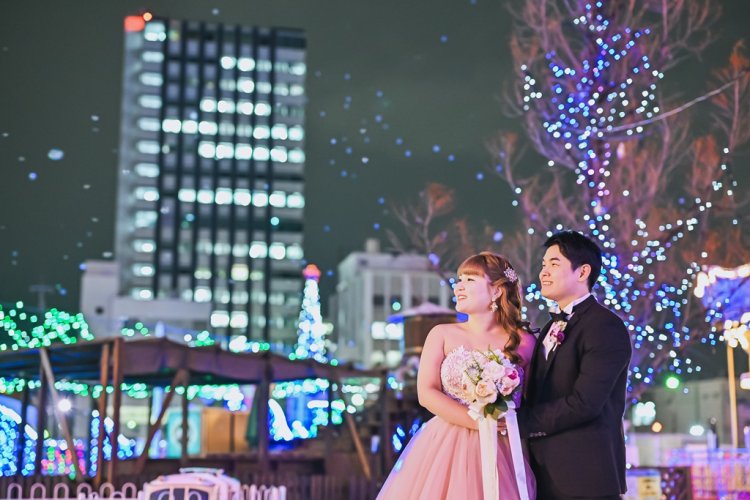 イルミネーションの遊園地を眺める新郎新婦