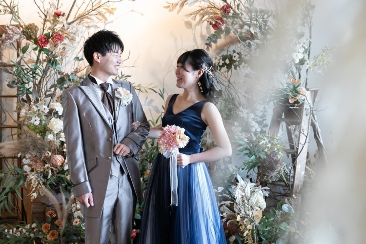 ドライフラワーの前で笑顔で見つめ合う新郎新婦