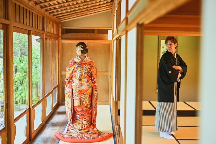 外を眺める新婦を見つめる新郎