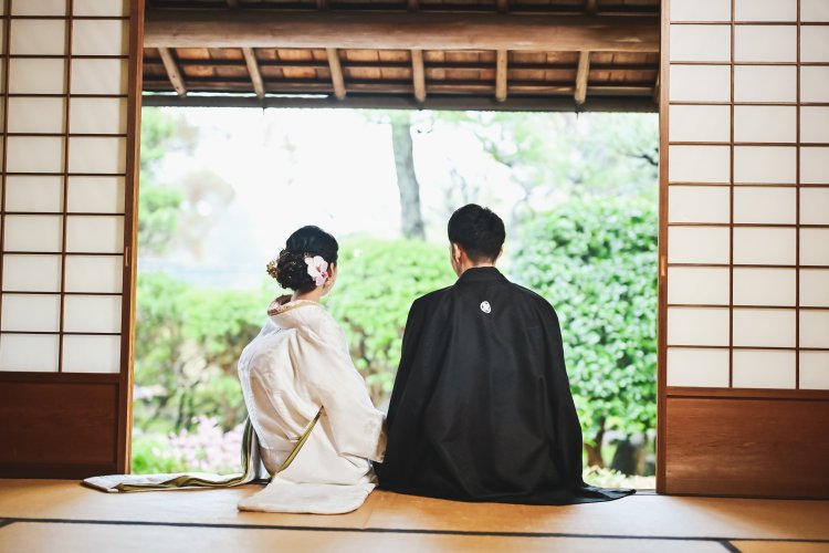 縁側で景色を眺める和装姿の新郎新婦後ろ姿