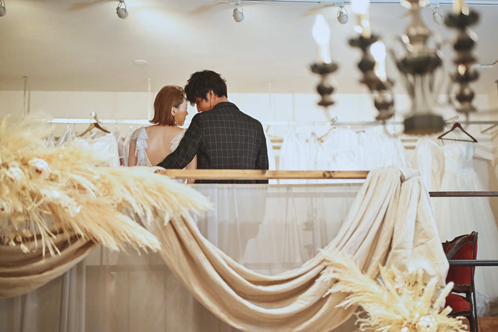 シャンデリアとカーテン越しで肩を寄せる新郎新婦