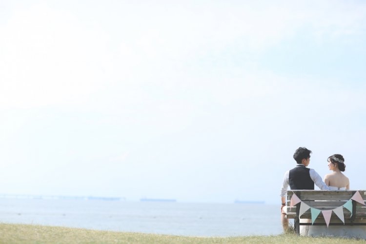 芝生のベンチで仲良く座る新郎新婦