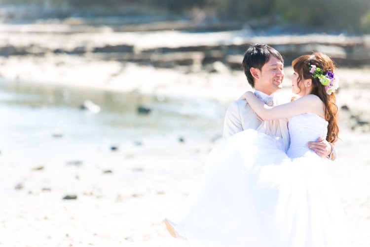 海辺でお姫様抱っこで幸せそうな新郎新婦