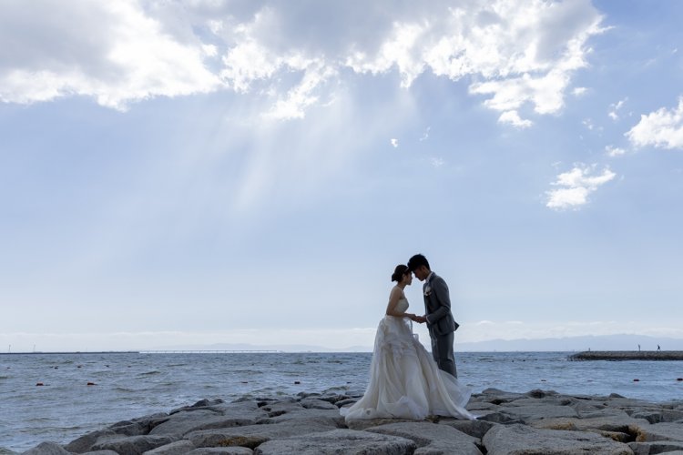 海をバックに手を取り合っておでこを合わせる新郎新婦