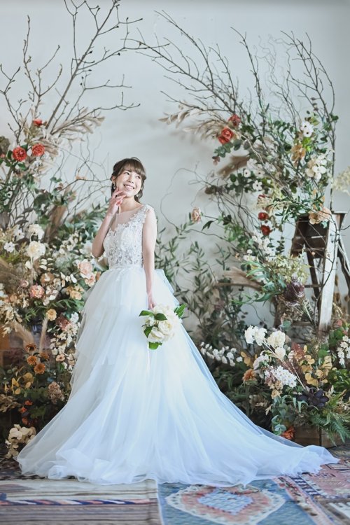 ドライフラワーバックにウェディングドレスでポージング
