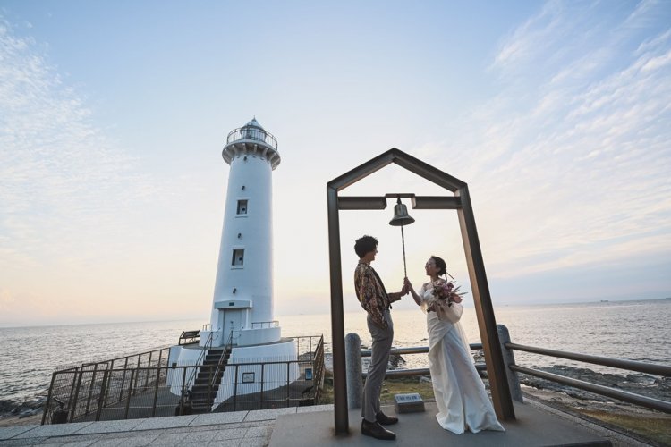 灯台にある鐘を一緒にならす新郎新婦