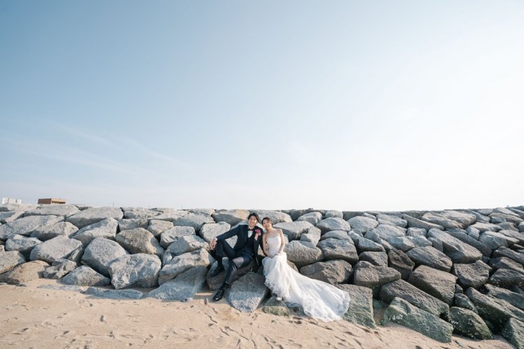 岩場で仲良く座って笑顔を向ける新郎新婦