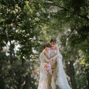 緑の中でおんぶして楽しそうな新郎新婦