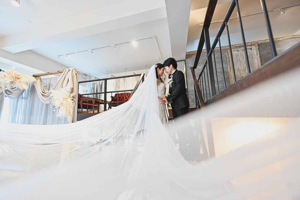 階段でヴェールを綺麗になびかせる新郎新婦