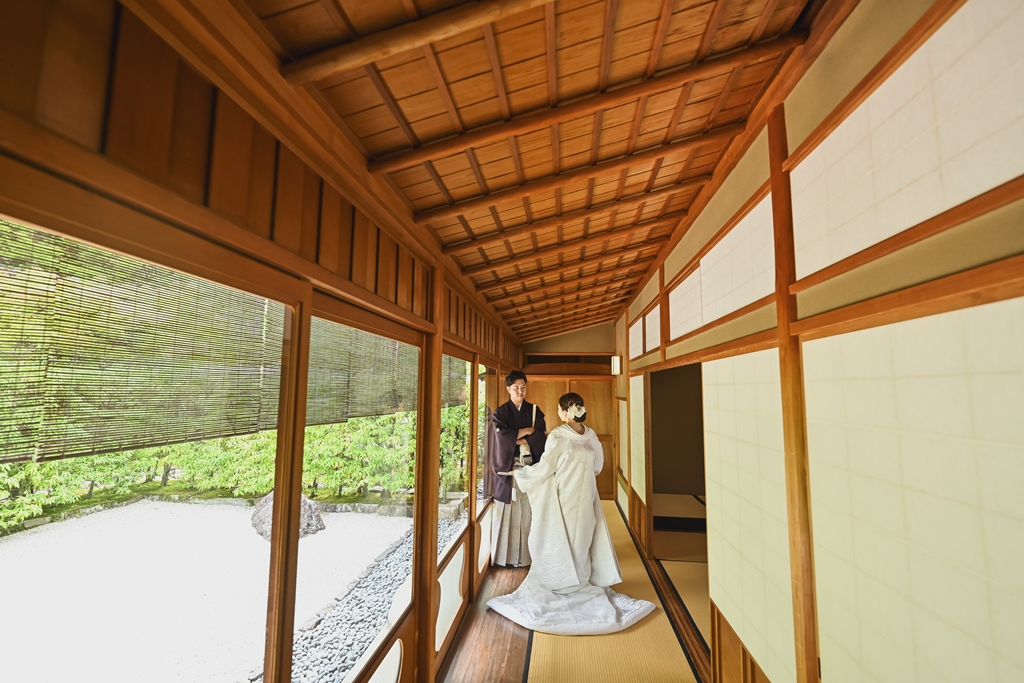 縁側でポーズをとる新婦とそれを見守る新郎