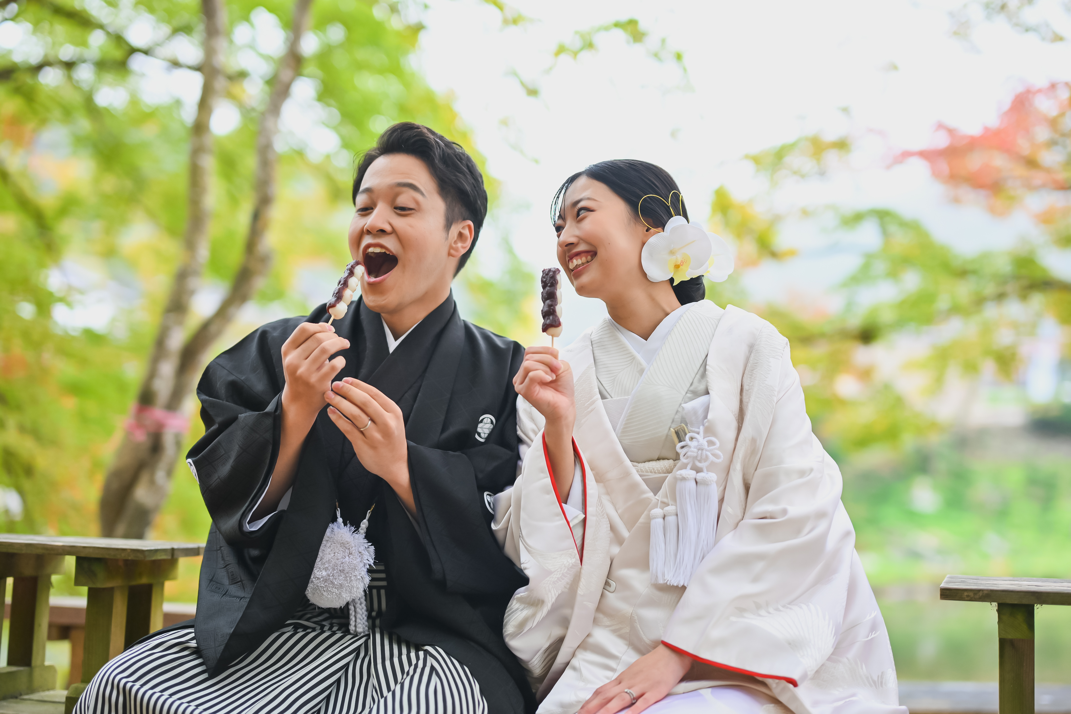紅葉のトンネルの下を手を取り合って歩くポーズの新郎新婦
