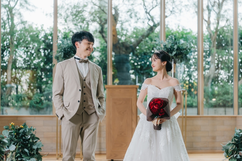 ドレスとタキシード姿で向かい合って微笑み合うポーズの新郎新婦
