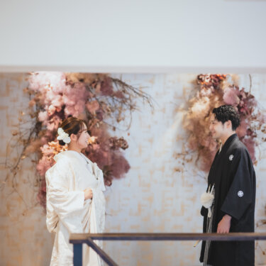 背を向けて待つ紋付袴の新郎に近づく白無垢の花嫁。ドライフラワーの前で撮るファーストミートの和装前撮り
