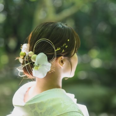 胡蝶蘭と水引の髪飾りをつけた、白無垢の花嫁の後ろ姿。和装前撮りで映えるヘアアレンジ