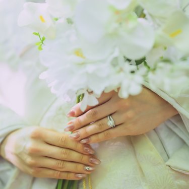 胡蝶蘭のブーケを持つ花嫁の手元と指輪、白無垢の地紋を写したクローズアップの和装フォトウェディング