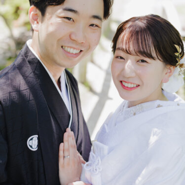 新郎の胸に手を添え、頬を寄せてカメラに笑う白無垢の花嫁と紋付袴の新郎のアップの和装前撮り