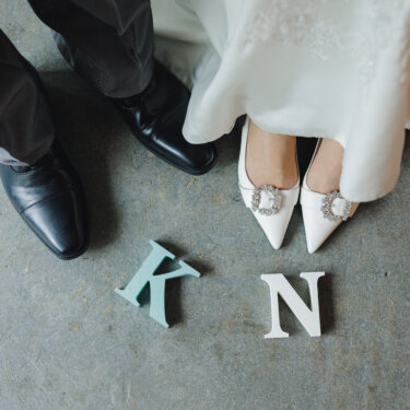 'K''N'のイニシャルオブジェと、新郎の革靴、ビジューのついた花嫁の靴を写した足元のカット。前撮りのアイテム