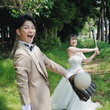 木立の中でバットを振るウェディングドレスの花嫁と、グローブでボールを受ける新郎。野球好きの二人らしいウェディングフォト