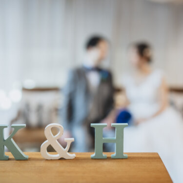 手前の'K&H'のイニシャルオブジェにピントを合わせ、奥の新郎新婦をぼかしたおしゃれな前撮り