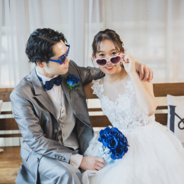 'Mr''Mrs'のクッションが並ぶベンチで、ハートや青いサングラスをずらしておどける新郎新婦の前撮り