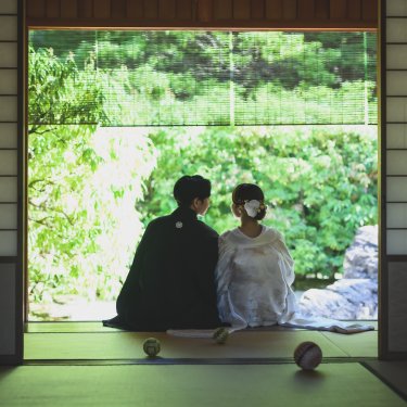 障子を開けた和室から、縁側に並んで庭を眺める新郎新婦の後ろ姿を写した和装フォトウェディング