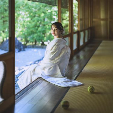 畳の縁側に腰かけ、振り返ってほほえむ白無垢の花嫁。手毬が転がる和室で撮る和装前撮り