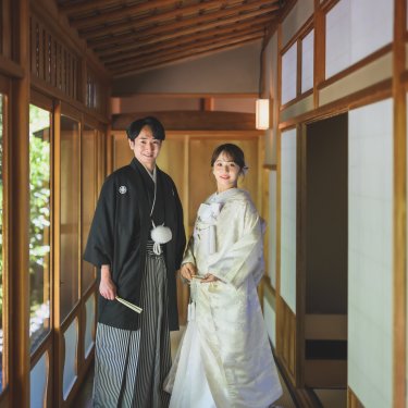 数寄屋の廊下に並んで立つ紋付袴の新郎と白無垢の花嫁。白鳥庭園で撮る和装フォトウェディング