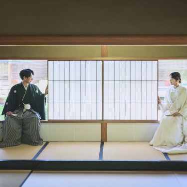 障子の和室の両端に離れて座る紋付袴の新郎と白無垢の花嫁。白鳥庭園の数寄屋で撮る和装前撮り